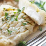 Pieczony filet z halibuta w naczyniu żaroodpornym, doprawiony ziołami i przyprawami.